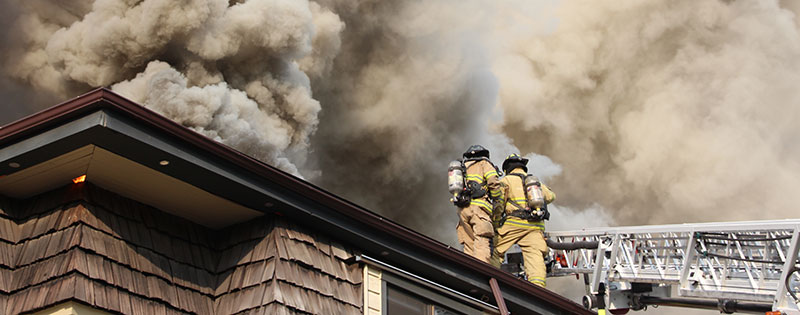 firefighters battling roof fire with smoke